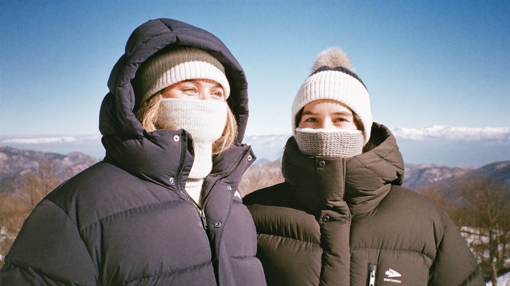 The image shows two people dressed warmly in a snowy mountai